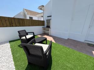 un patio avec trois chaises et de l'herbe dans l'établissement Sanbia - Comporta Beach House, à Carvalhal