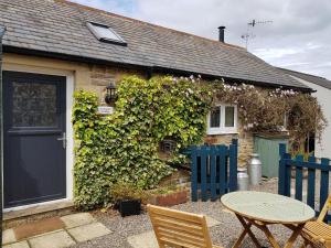una casa con una porta blu e un tavolo con sedie di Stanegate Cottage a Greenhead