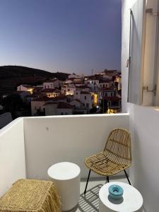 a chair and stool on a balcony with a view at Ola House Dryopida Kythnos in Dhriopís