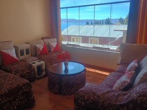 a living room with two chairs and a table and a large window at Luquina homestay in Puno