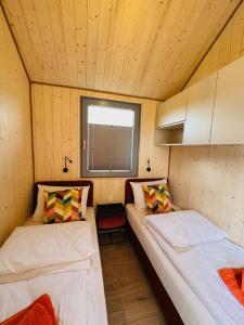 two beds in a small room with a window at Zagroda Sosnowa in Dębki