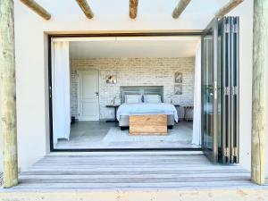 a bedroom with a bed and a door open to a patio at Wild Comforts at Springerbaai in Boggomsbaai