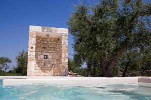 a swimming pool with a tower next to a tree at Apulia Relais in Alberobello