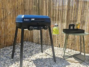 a blue grill and a stool next to a fence at Tiny Loft Šamorín - s privátnym wellness, saunou a vírivkou in Šamorín