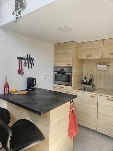 a kitchen with wooden cabinets and a black counter top at Tiny Loft Šamorín - s privátnym wellness, saunou a vírivkou in Šamorín