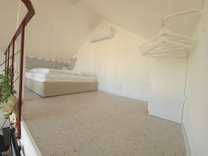 a white room with a bed and a mirror at Tiny Loft Šamorín - s privátnym wellness, saunou a vírivkou in Šamorín