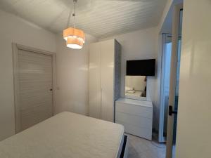 a white room with a bed and a tv and a table at rupea breeze home in Tropea