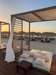 a white bed sitting on a deck next to the beach at Luxurious Chalet GAIA Ras El Hekma North Coast in Zāwiyat al ‘Awwāmah
