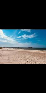 vistas a una playa de arena con cielo azul en Apartament z widokiem na las, en Ustka