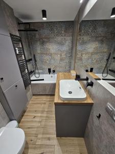 Un baño con lavabo, inodoro y bañera. en Apartament z widokiem na las, en Ustka