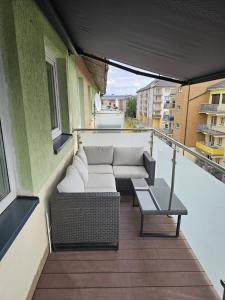 - Balcón con sofá y mesa en un edificio en Apartament z widokiem na las, en Ustka