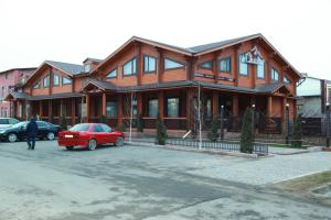 duży drewniany dom z samochodami zaparkowanymi przed nim w obiekcie Guest House Chalet w mieście Taraz