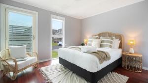 een slaapkamer met een bed, een stoel en een raam bij Lakeview Retreat in Culburra Beach