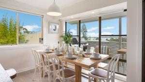 een eetkamer met een houten tafel en stoelen bij Lakeview Retreat in Culburra Beach