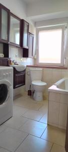 a bathroom with a toilet and a sink and a washing machine at Apartament na Sienkiewicza in Leśna