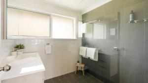 een witte badkamer met een wastafel en een douche bij Lakeview Retreat in Culburra Beach +31 foto's