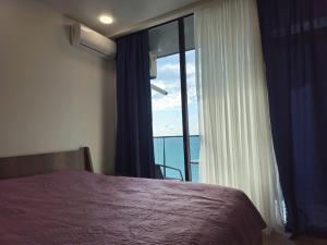 une chambre avec un lit et une grande fenêtre dans l'établissement NBG Apartments, à Batoumi