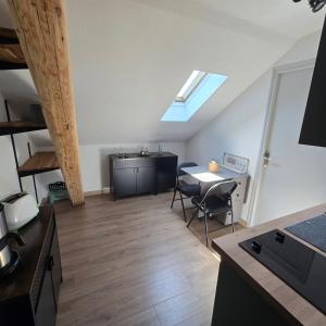 a room with a table and chairs and a skylight at Petit appartement 1 Le charmant in Sarreguemines
