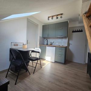 a kitchen with a table and chairs in a room at Petit appartement 1 Le charmant in Sarreguemines +4 photos