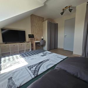 a bedroom with a large bed and a flat screen tv at Petit appartement 1 Le charmant in Sarreguemines
