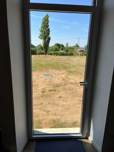 une vue d'une fenêtre sur un champ à travers une porte dans l'établissement La petite maison de campagne, à La Celle-sous-Gouzon