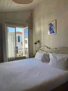 a bedroom with a large white bed and a window at Chambre d'hôtes Hôte des Portes Île de Ré in Les Portes