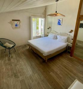 a bedroom with a white bed and a chair at Chambre d'hôtes Hôte des Portes Île de Ré in Les Portes