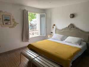 a bedroom with a bed with a yellow blanket and a window at Chambre d'hôtes Hôte des Portes Île de Ré in Les Portes