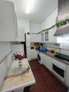 a kitchen with white cabinets and a vase of flowers on a table at Perfect Room Near Airport 1 in Lisbon +12 photos