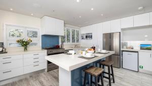 a kitchen with white cabinets and a island with stools at Sandy Point Escape in Corlette