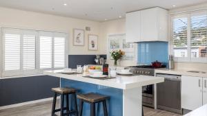a kitchen with white cabinets and a island with stools at Sandy Point Escape in Corlette