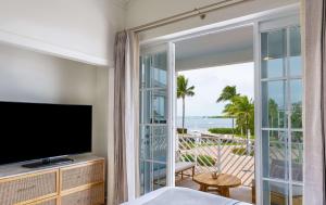 ein Schlafzimmer mit einem TV und einem Balkon mit Meerblick in der Unterkunft Bayside Villas by Islander Resort in Islamorada