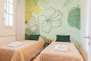 two beds in a room with flowers on the wall at Fliphaus Mansion Paz A 10 pax Deluxe House Belgrano in Buenos Aires