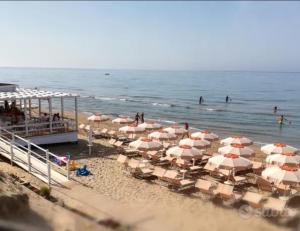 a bunch of umbrellas on a beach with the ocean at La casa al mare int2 in Lido Di Fondi +10 photos