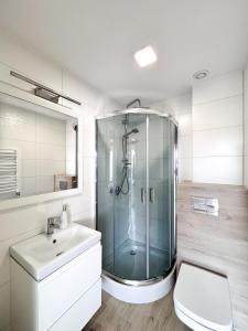 a bathroom with a glass shower and a sink at Dom Wczasowy Natalia in Łeba +55 photos