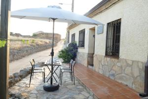 ein Tisch und Stühle mit einem Sonnenschirm auf einer Terrasse in der Unterkunft Casa Escalones in Villalba