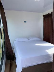 a white bed in a room with a window at Hostal pura vida in San Bernardo del Viento +7 photos