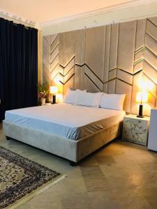 Un dormitorio con una cama grande con dos lámparas. en Dazzy Dream Guest Houses, en Islamabad