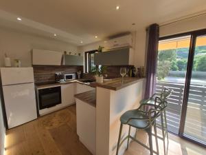 a kitchen with white cabinets and a counter with stools at Studio cosy climatisé in Lucciana +15 photos