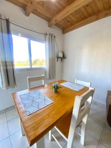 a wooden dining room table with two chairs and a window at Duplex Urbano in Puerto Iguazú