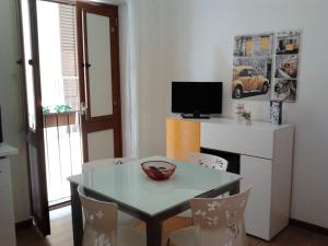 una sala da pranzo con tavolo, sedie e TV di Casa Vacanza Le Farfalle a Trapani