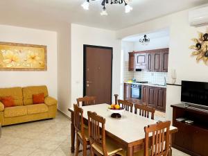 a kitchen and living room with a table and a couch at Ros House - Grande Appartamento con Veranda & balcone in Uggiano la Chiesa