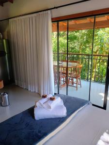 a bedroom with a bed and a balcony with a table at Lindo Chalé a 7 minutos do Centro in Domingos Martins +3 photos