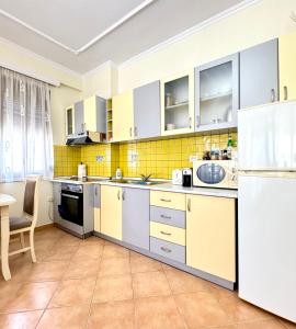 a kitchen with white appliances and yellow tiles at Four Seasons Beach Apartment Golem in Golem