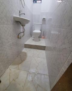 a white bathroom with a sink and a toilet at Appartement Amani in Kinshasa +3 photos