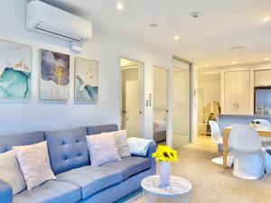 a living room with a blue couch and a table at High-Floor 2BR Apt Sky Tower view AC Pool Gym in Auckland