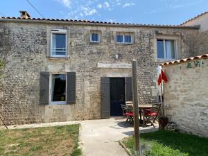 a stone house with a table in front of it at 3 étoiles entre terre et mer jolie maison in Saint-Just