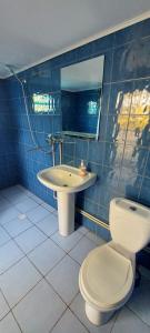 a blue tiled bathroom with a toilet and a sink at ДАЧА на Студенческой in Karolino-Buhaz