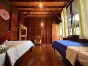 Passiflora Lodge Tambopata في بويرتو مالدونادو: غرفة نوم بها سريرين في غرفة ذات جدران خشبية