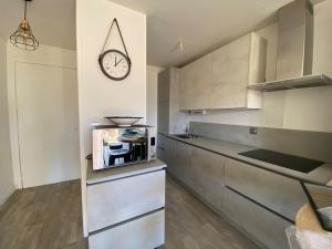 a kitchen with a clock on the wall at Sea Breeze Gujan-Mestras in La Celle-sous-Gouzon